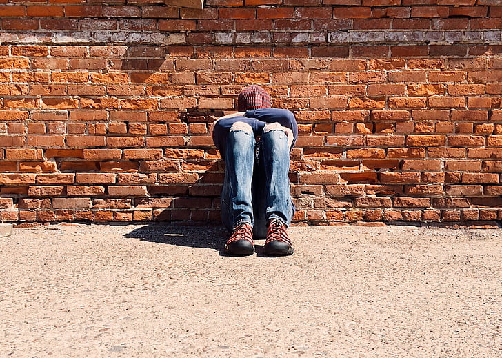 person, young, sitting, hiding, bullied, sad, brick wall