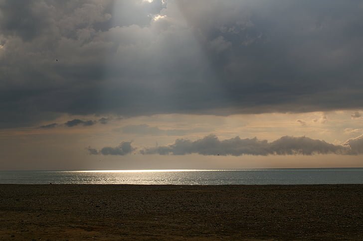 beach, sun's rays, sea, reflections on the water, dark clouds, sand, pebble