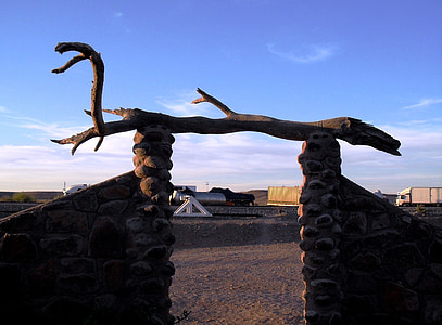 entrada, muros de pedra, madeira petrificada, madeira seca, areia, céu azul, fim de tarde