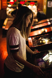 woman, white, shirt, standing, facing, arcade, machine