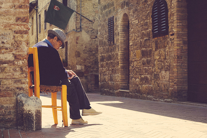 old, man, fedora, sitting, chair, street, cobblestone