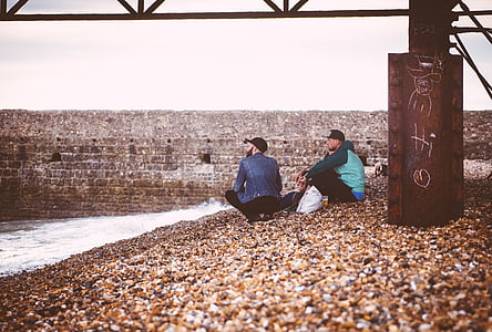 two, men, sitting, rocks, behind, metal, post