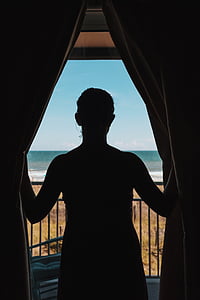 silueta, persona, apertura, cortina, balcón, buscando, mar