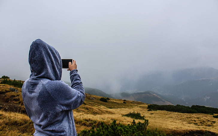 person, holding, smartphone, taking, photo, people, hoodie