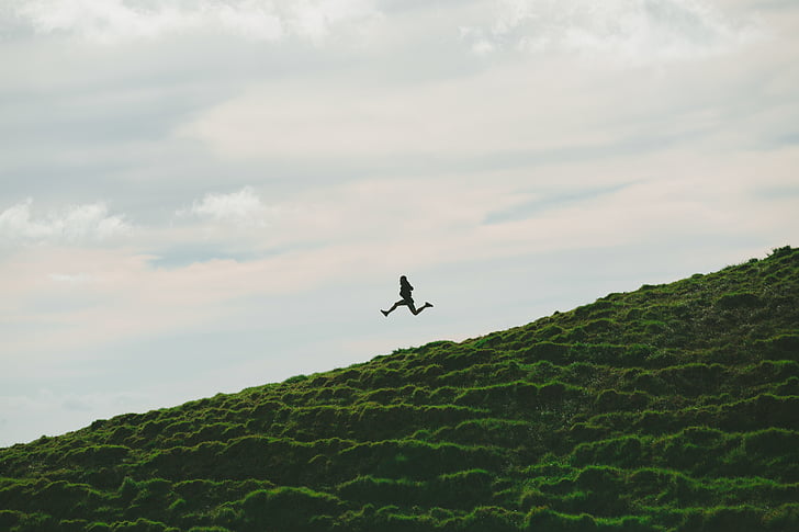 person, jumping, green, grass, field, daytime, cloud