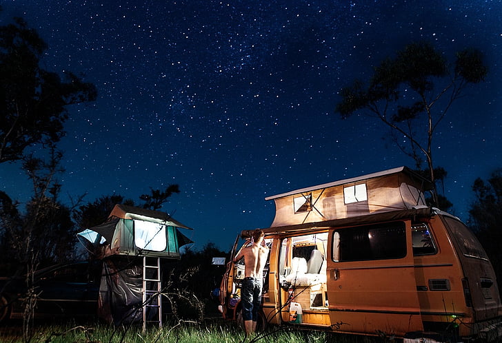 photo, man, standing, front, rv, nighttime, camping