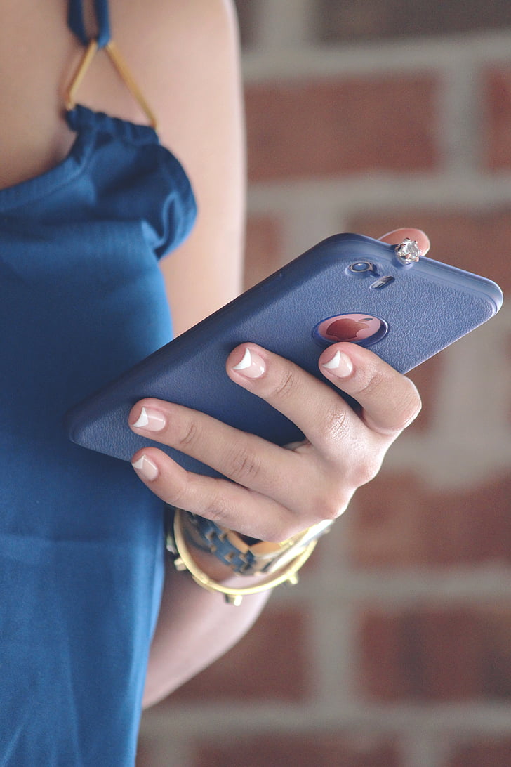 blue sleeveless, blurry, bracelet, brick wall, cellphone, close-up, device