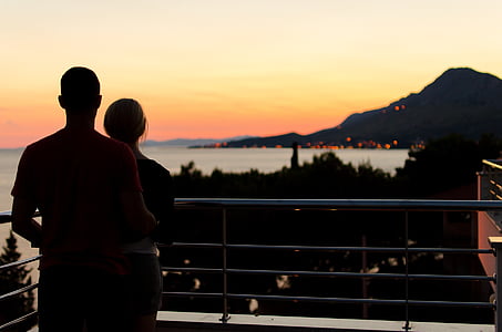 σιλουέτα, ζευγάρι, στέκεται, βεράντα, κοντά σε:, στη θάλασσα, ηλιοβασίλεμα