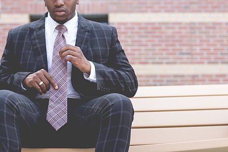 man, black, grey, checked, suit, sitting, holding