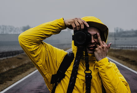 person, holding, dslr, wearing, yellow, hoodie, middle