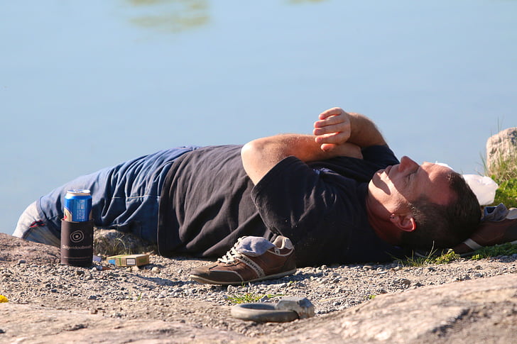 water, ground, man, beer can, cigarette box, shoes, socks
