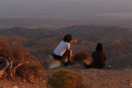 people, sitting, gray, soil, daytime, hills, desert