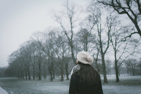 vrouw, staande, in de buurt van, verwelkte aren, boom, sneeuw, tijd