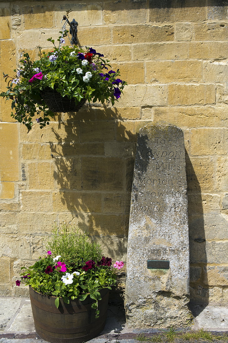 very old distance marker, carved stone, historic, yellow stone wall, hanging basket, planter tub, broadway