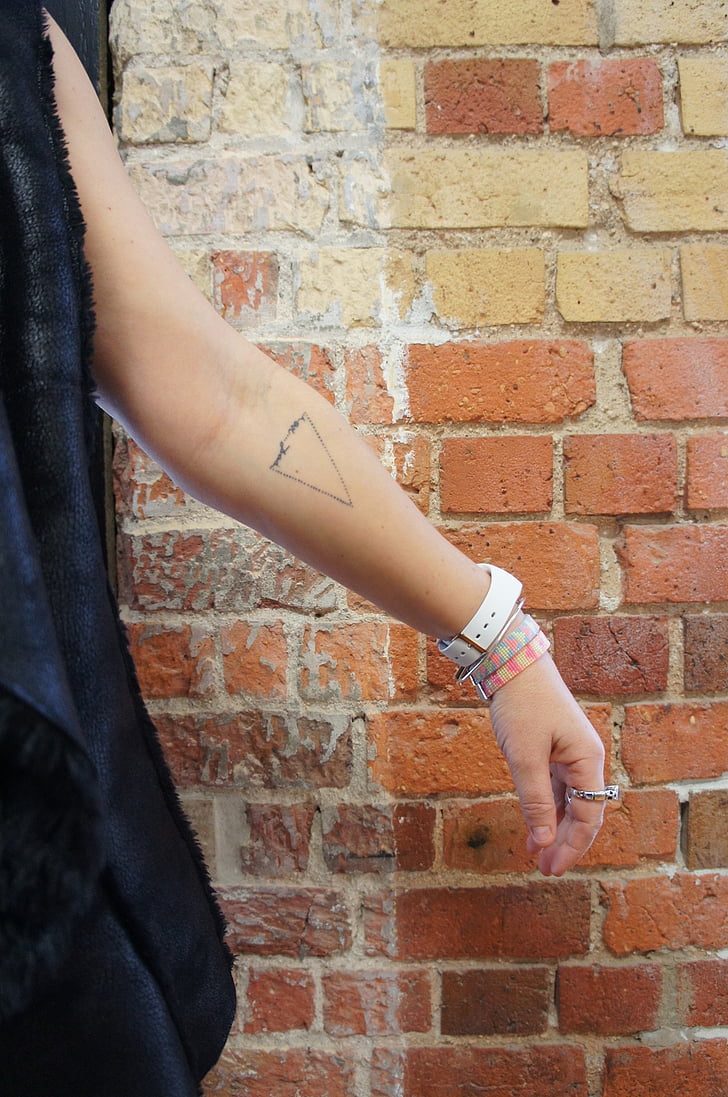 small tattoo, arm, watch, brick wall, indoors, brick, human body part