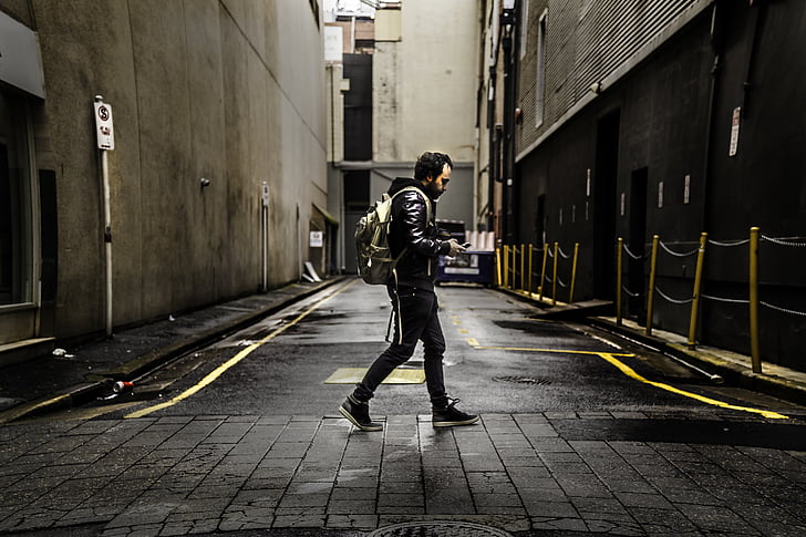 man, wearing, backpack, walking, street, using, phone
