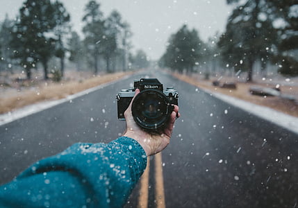person, holding, nikon, camera, snowing, daytime, lens