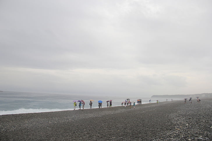 Beach, zamračený deň, vietor fúka, niekoľko ľudí na pobreží, tajomné a krásne