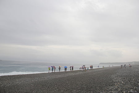 praia, dia nublado, o vento sopra, várias pessoas ao longo da costa, misteriosa e bela