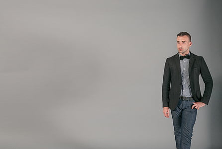 man, black, blazer, jeans, standing, gray, background