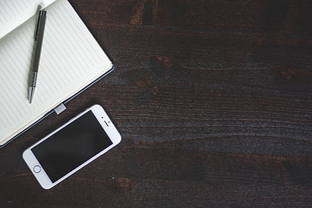 argento, iPhone, vicino a, Notebook, marrone, in legno, superficie