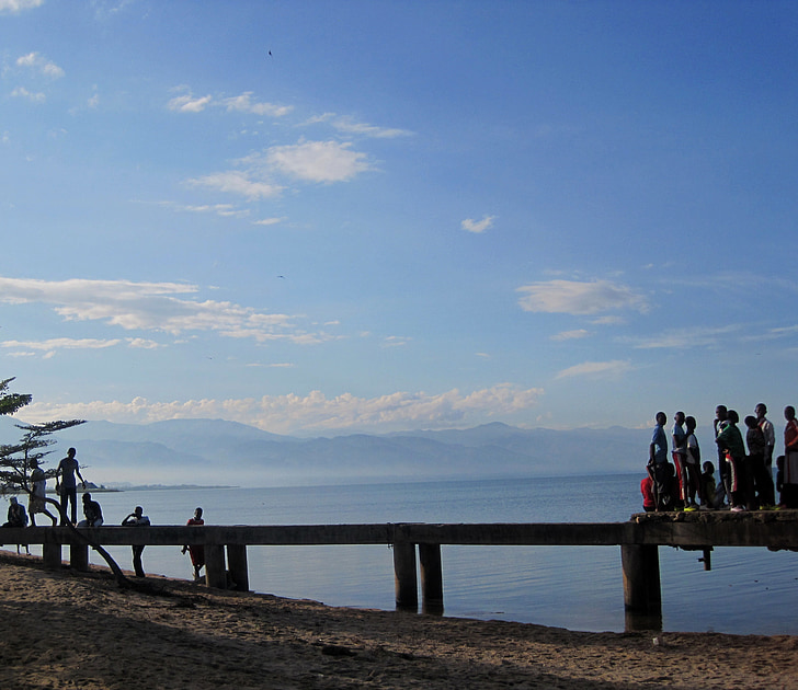 africa, distant mountain range, few clouds, blue sky, jetty, blue water, snady shore