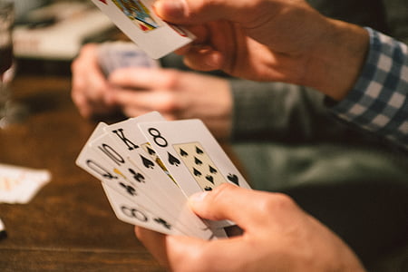 person, holding, playing, cards, sitting, beside, table