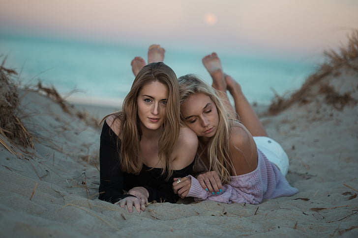 selective, focus, photography, two, women, lying, sand