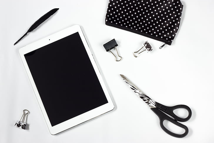 tablet, work desk, a pair of scissors, a feather, ipad, electronic equipment, black and white