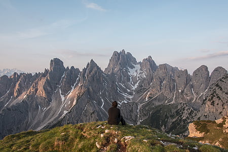 man, seating, grass, front, mountains, daytime, mountain