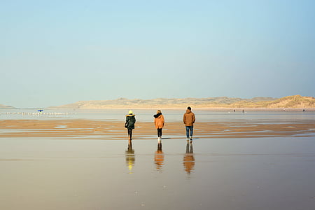 trois, personne, portant, chandail à capuchon, marche, Wet, sable