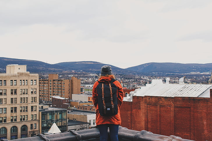 backpack, buildings, city, mountains, person, sky