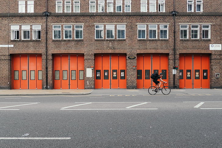 bicycle, bike, building, cyclist, parking lot, person, windows