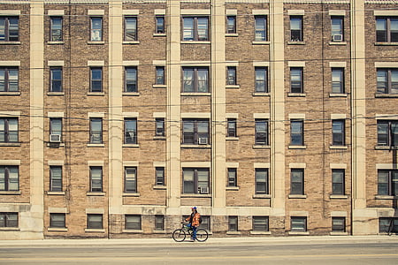 man, riding, bicycle, near, high, rise, building