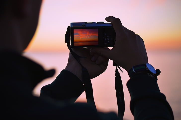man, holding, digital, camera, capturing, sun, set