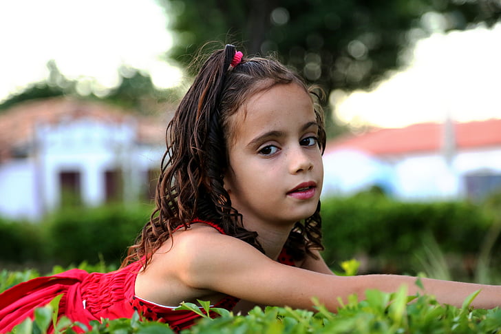 nena mirant de perfil, noia al jardí, model de, nen, família, herba verda, vestit vermell