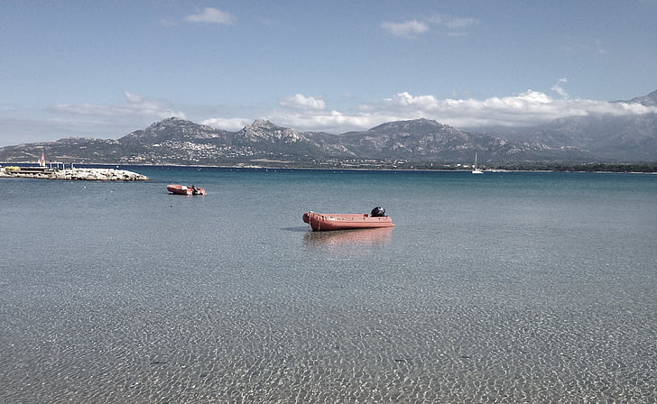 brown, inflatable, boat, sea, near, mountains, daytime