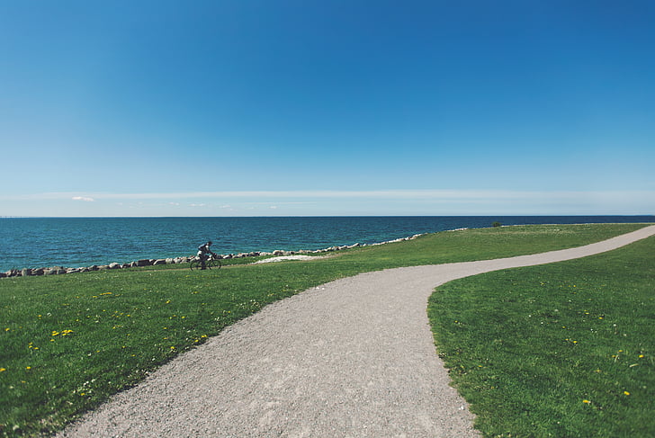 person, riding, bike, near, sea, gravel, trail