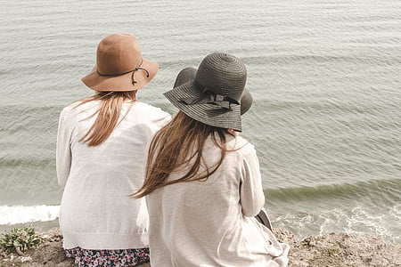Fotoğraf, iki, kadın, oturma, deniz kıyısı, giyiyor, şapka