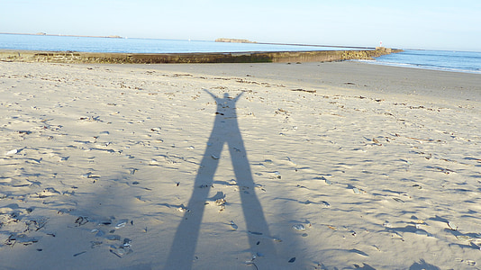 Shadow mannen, människans skugga i sand, skuggspel, havet, stranden, naturen, kusten