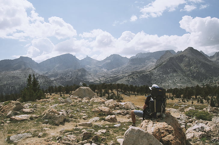 person, sitting, brown, stone, daytime, mountains, hiking