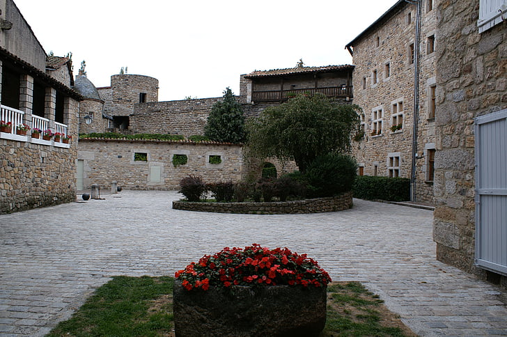 antiguo edificio, piedras, pueblo francés, patio, flores rojas, árboles, vieja torre