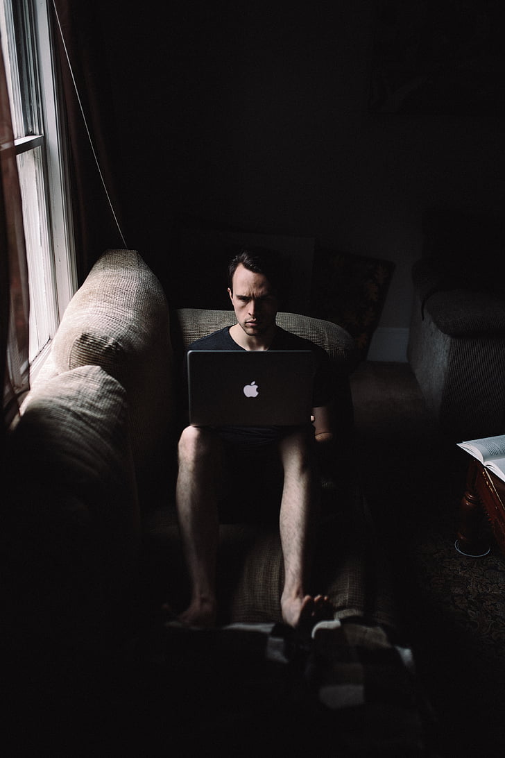home, utilitzant, MacBook, assegut, al costat de, vidre, finestra